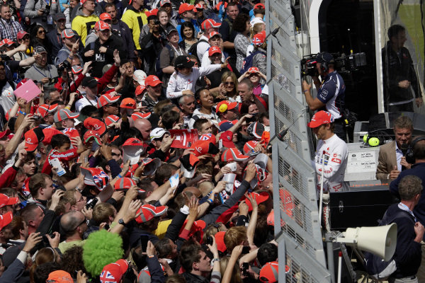 Jenson Button signs autographs to the fans clamouring against the pit wall.