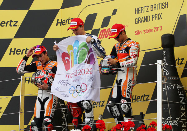 British Grand Prix. 
Silverstone, England. 30th August - 1st September 2013. 
Jorge Lorenzo, Yamaha, Marc Marquez and Dani Pedrosa, Honda, on the podium with a flag to support Madrid's bid to host the 2020 Olympic games. 
Ref: IMG_2560a. World copyright: Kevin Wood/LAT Photographic